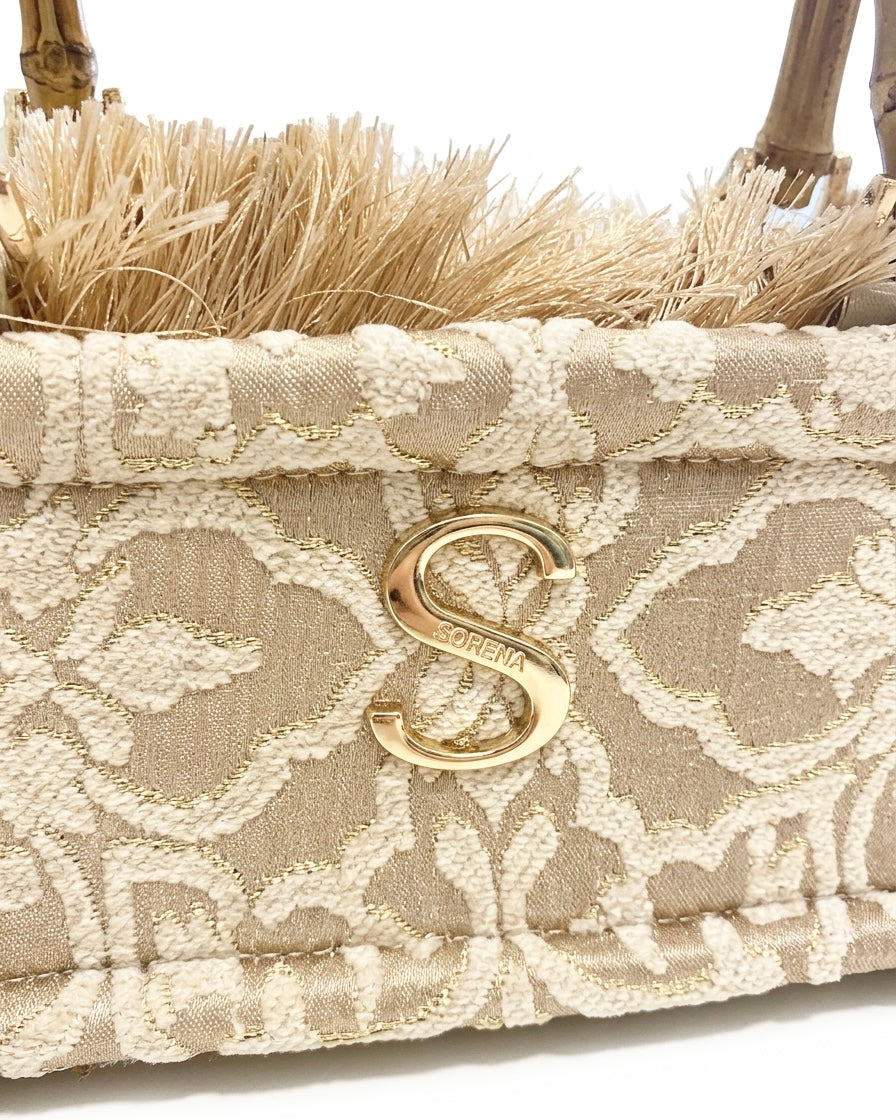 Borsa a mano e tracolla Sorena prodotta in Grecia in tessuto jacquard damascato beige e oro con manico in bamboo, frange e logo S dorato - Buttò Calzature - logo.