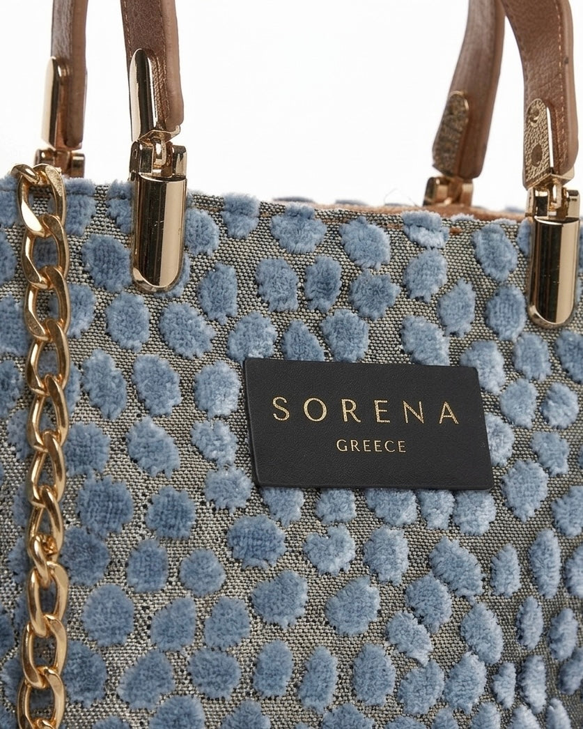 Borsa a mano Sorena prodotta in Grecia in tessuto jacquard vellutato azzurro avio a pois con manici nude cammello, etichetta nera e catena dorata - Buttò Calzature - logo.