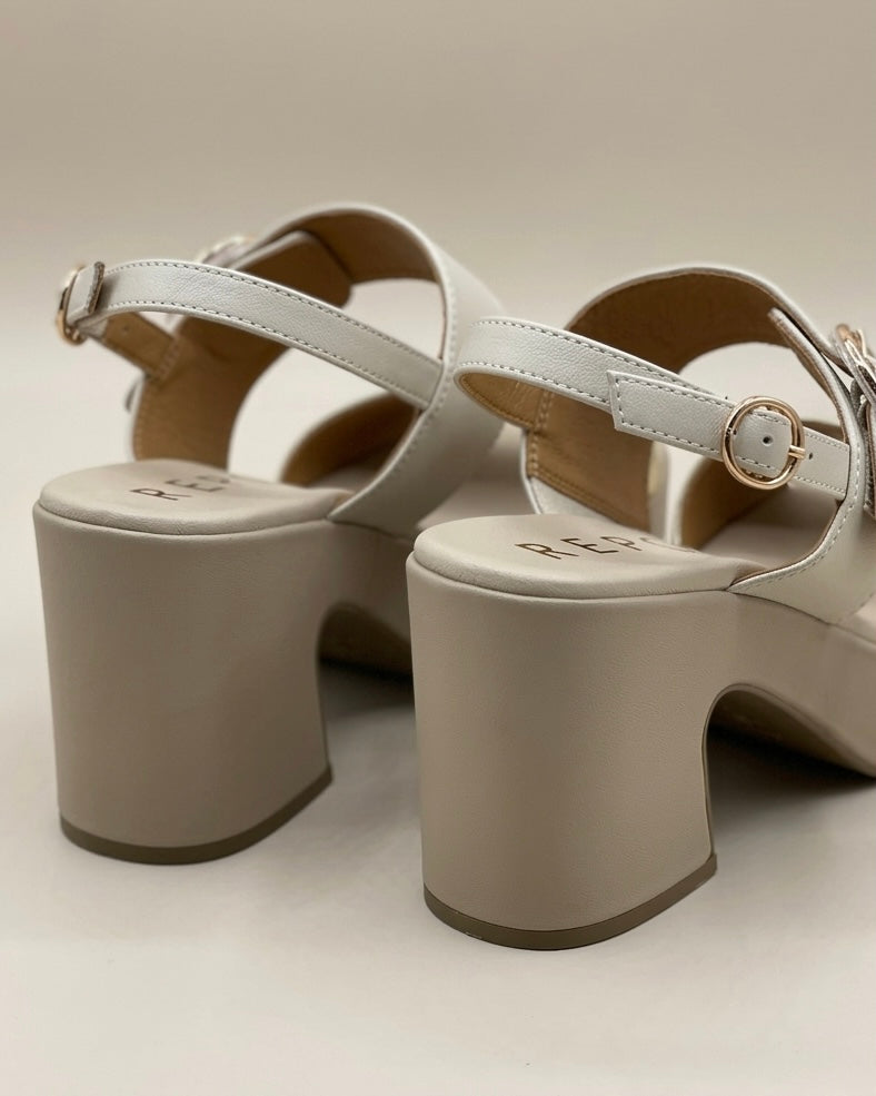 Sandali da donna marca REPO con platform beige, fascia anteriore dorata metallizzata, cinturino bianco avorio con fibbia circolare oro e tacco largo e comodo-retro tacco.