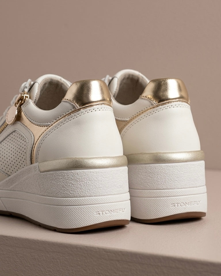 Sneakers Stonefly da donna in pelle bianca traforata con eleganti finiture oro, zeppa ammortizzata e zip laterale-retro scarpa.