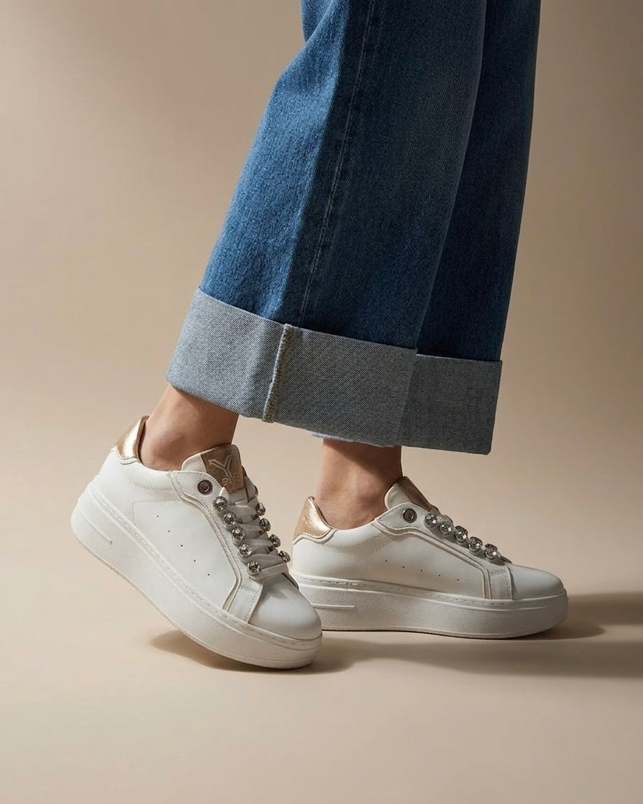 Sneakers donna bianche brand KEYS con grandi castoni gioiello sui lacci, linguetta e tallone oro rose lucido, suola platform panna - indossate.