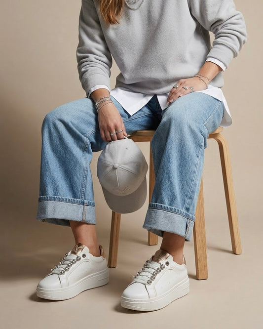 Sneakers donna bianche brand KEYS con grandi castoni gioiello sui lacci, linguetta e tallone oro rose lucido, suola platform panna - modella.