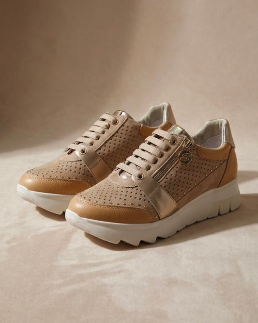Sneakers Stonefly da donna color sabbia con pelle traforata, dettagli laminati oro, suola bianca sagomata e pratica zip laterale.