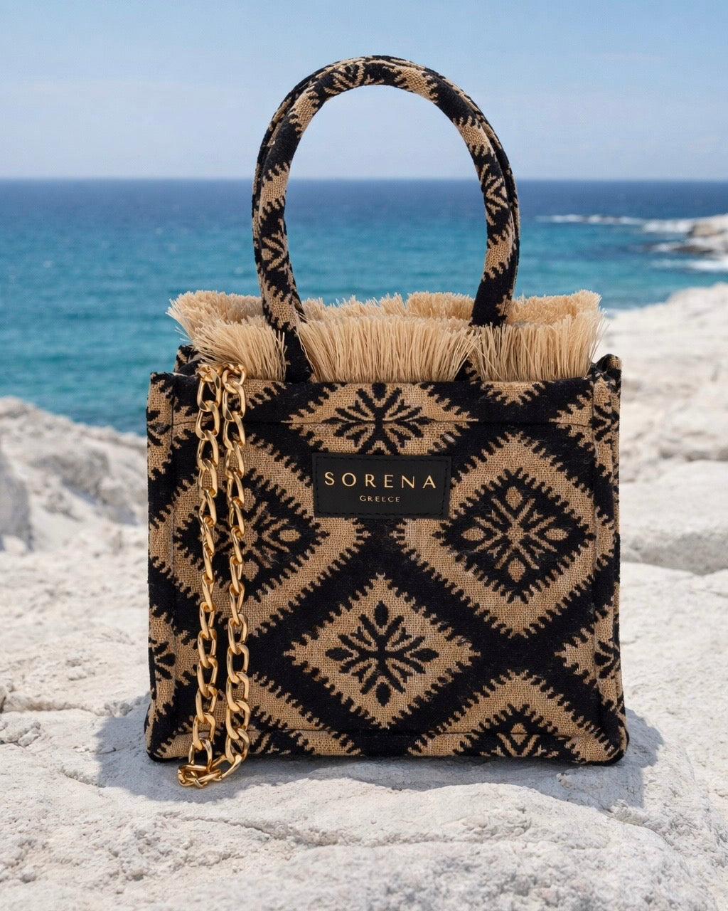 Borsa a mano Sorena prodotta in Grecia in tessuto jacquard geometrico nero e beige con frange dorate e manici in tinta - Buttò Calzature.