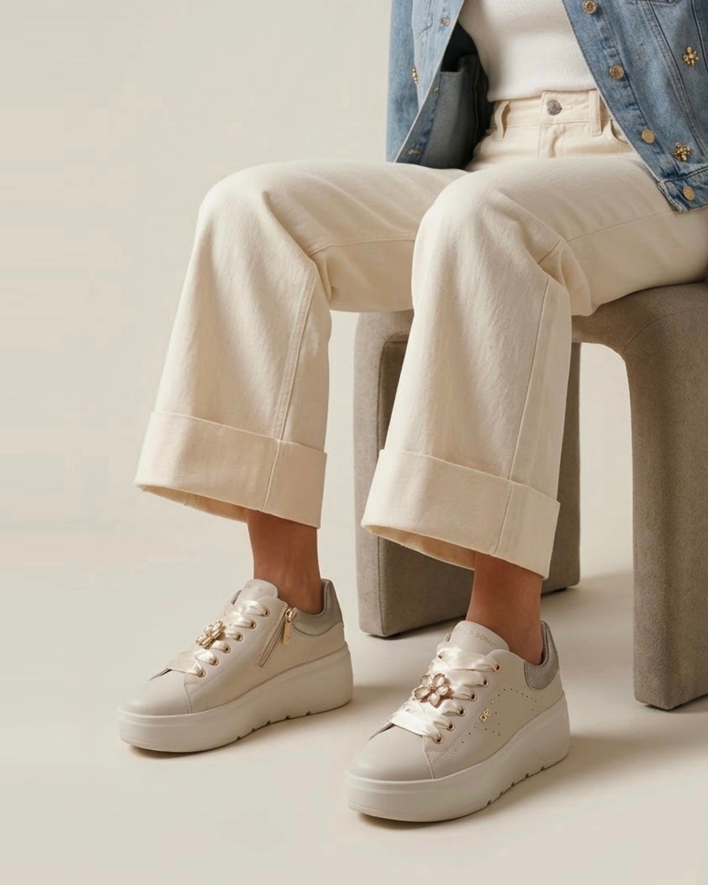 Sneakers platform da donna Donna Serena color panna in pelle, con lacci larghi in raso lucido, applicazione a forma di fiore gioiello e tallone argentato - modella.