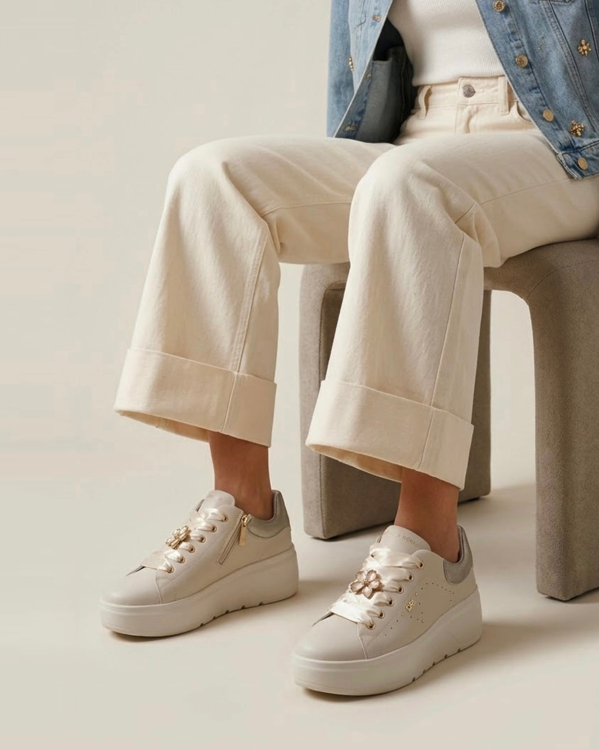 Sneakers platform da donna Donna Serena color panna in pelle, con lacci larghi in raso lucido, applicazione a forma di fiore gioiello e tallone argentato - modella.