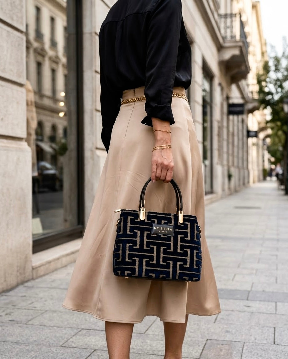 Borsa a mano Sorena prodotta in Grecia in tessuto jacquard vellutato con motivo geometrico greco nero e beige, manici neri e tracolla a catena dorata - Buttò Calzature - modella.