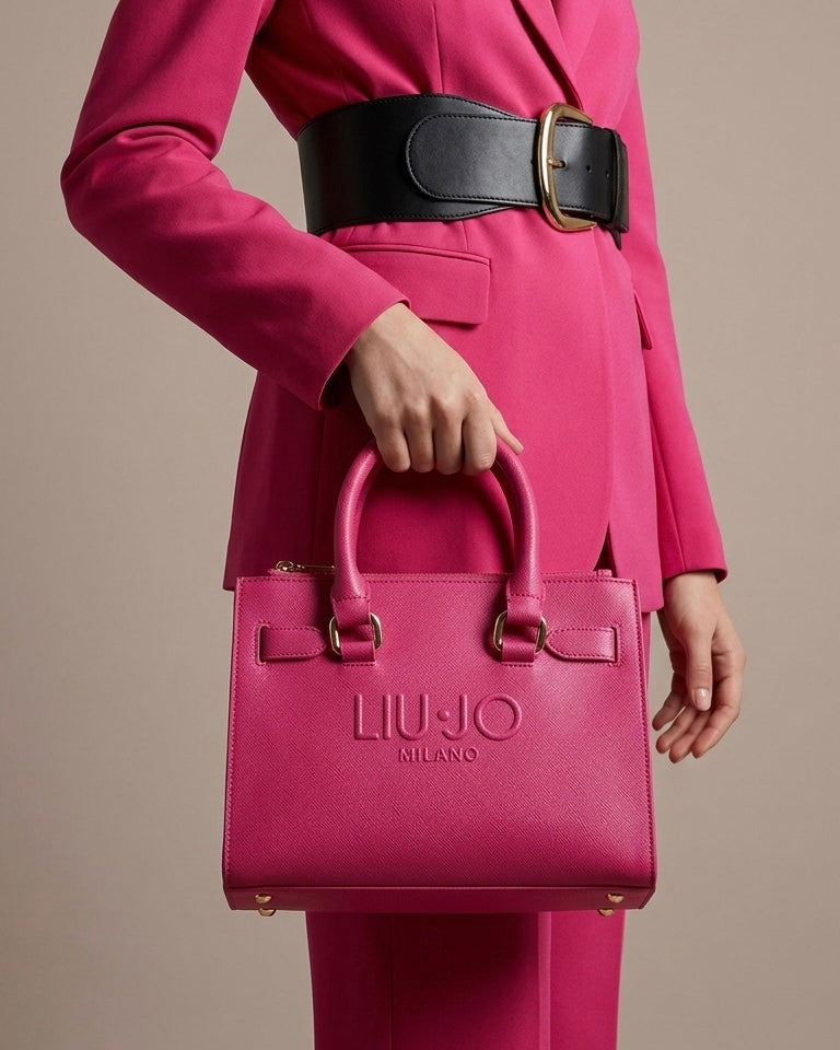 Borsa a mano rigida Liu Jo fucsia acceso con logo grande "LIU·JO MILANO" impresso in rilievo sul davanti, doppi manici e scomparti superiori con cerniere dorate-modella.
