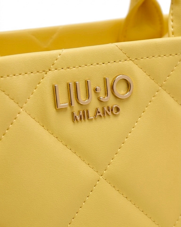 Borsa a mano Liu Jo color giallo sole con lavorazione trapuntata geometrica, logo frontale dorato "LIU·JO MILANO" e doppi manici rigidi-dettaglio logo.