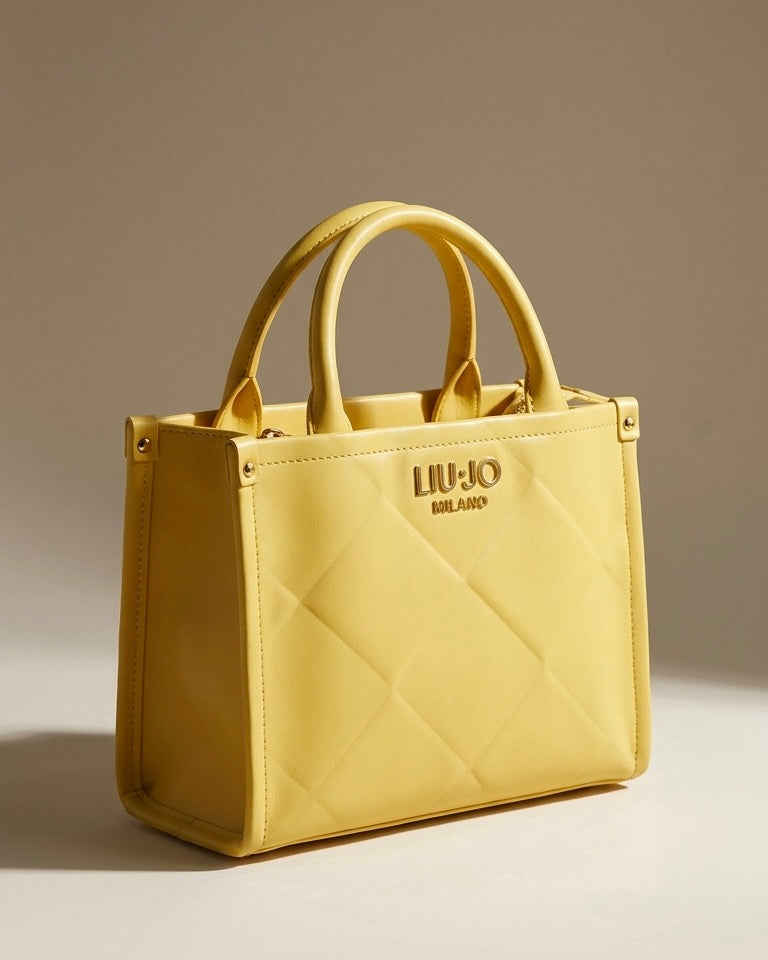 Borsa a mano Liu Jo color giallo sole con lavorazione trapuntata geometrica, logo frontale dorato "LIU·JO MILANO" e doppi manici rigidi.