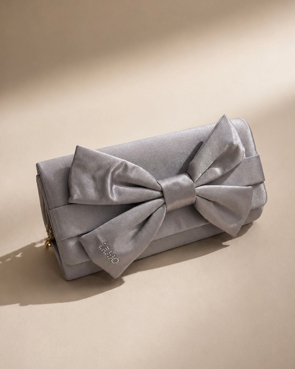 Borsa clutch Liu Jo in raso grigio argento con maxi fiocco frontale, logo in strass e tracolla a catena oro.