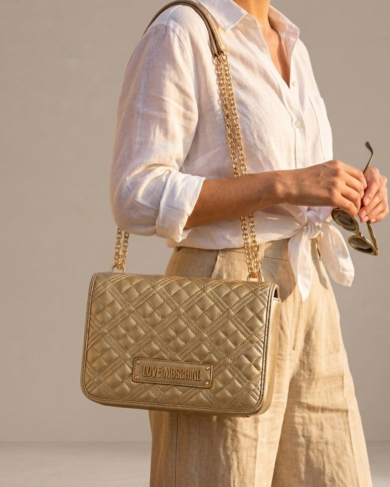 Borsa a spalla Love Moschino oro metallizzato con trapuntatura geometrica e tracolla a catena dorata-modella.