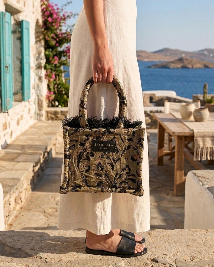 Borsa a mano Sorena prodotta in Grecia in tessuto jacquard damascato nero e oro con frange e manici in tinta - Buttò Calzature - modella.