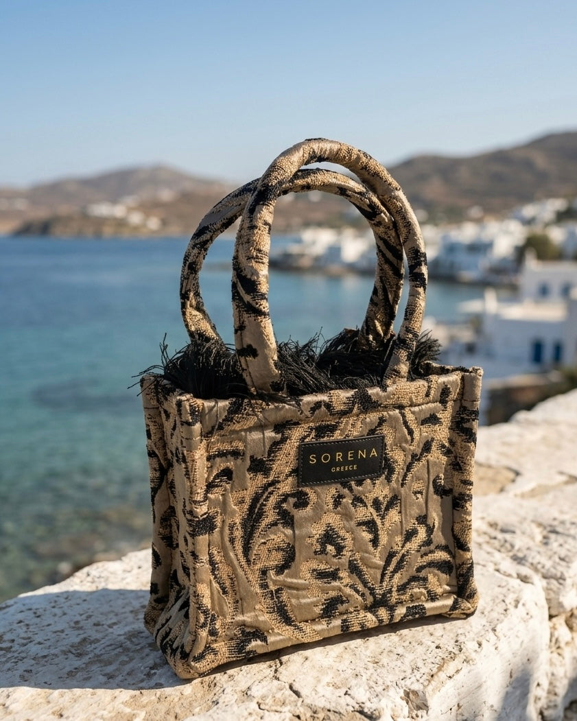 Borsa a mano Sorena prodotta in Grecia in tessuto jacquard damascato nero e oro con frange e manici in tinta - Buttò Calzature.