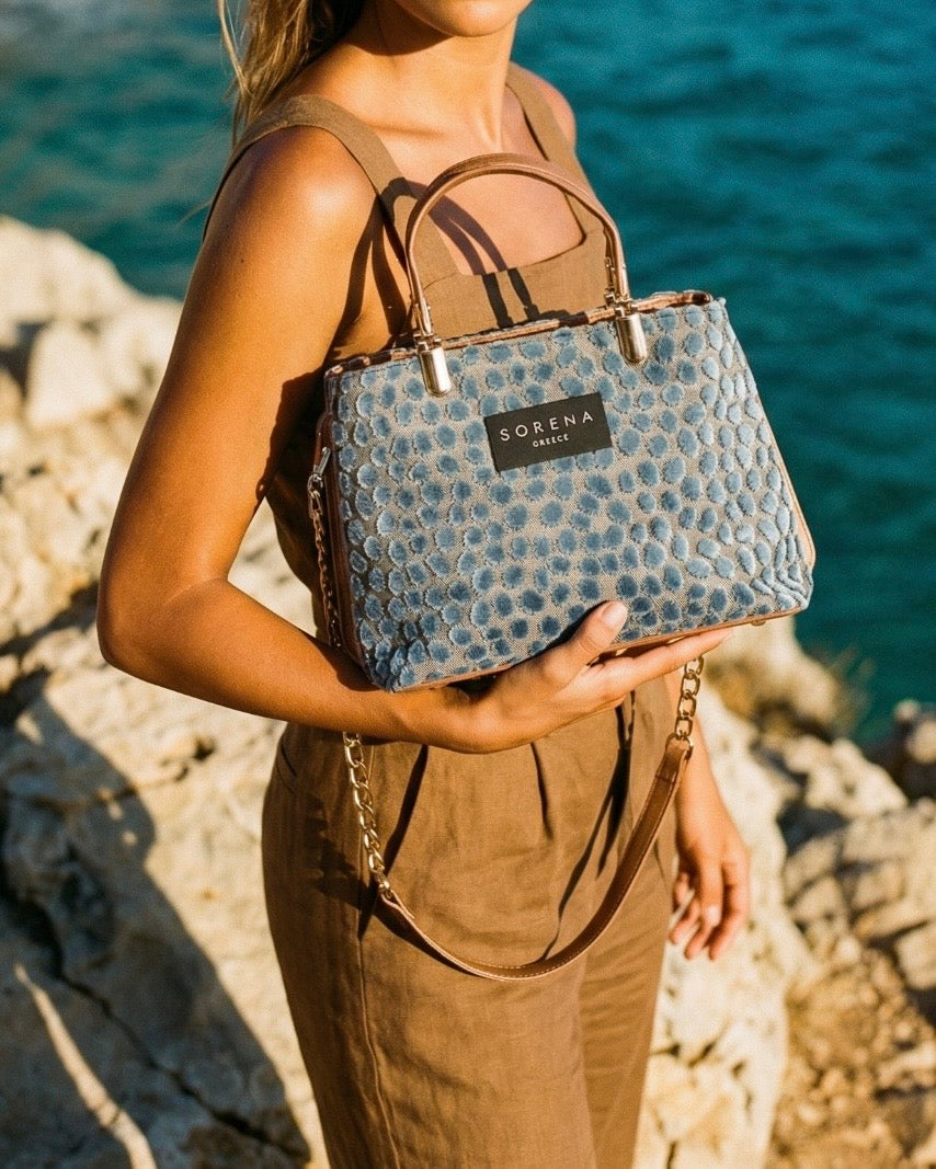 Borsa a mano Sorena prodotta in Grecia in tessuto jacquard vellutato azzurro avio a pois con manici nude cammello, etichetta nera e catena dorata - Buttò Calzature - modella.