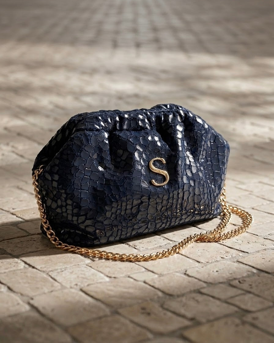 Borsa pochette clutch Sorena prodotta in Grecia con texture effetto coccodrillo blu notte, logo S e catena dorati - Buttò Calzature.