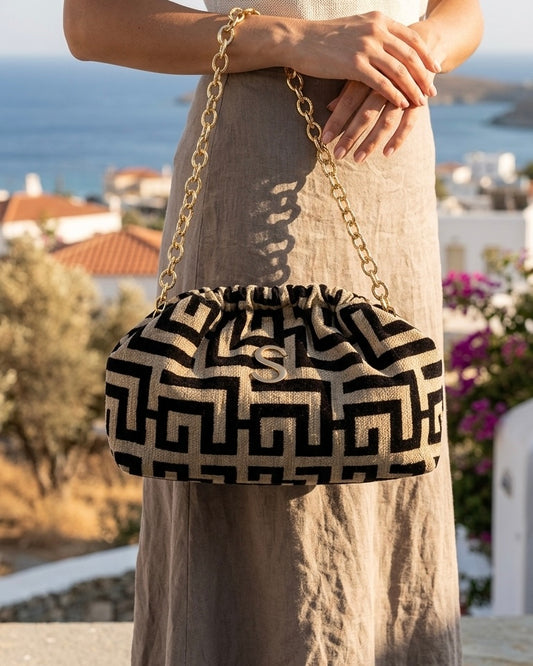 Borsa pochette clutch Sorena prodotta in Grecia in tessuto jacquard con motivo geometrico greco nero e beige, logo S e catena dorati - Buttò Calzature - modella.