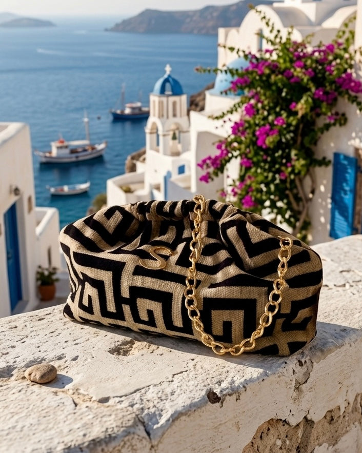 Borsa pochette clutch Sorena prodotta in Grecia in tessuto jacquard con motivo geometrico greco nero e beige, logo S e catena dorati - Buttò Calzature.