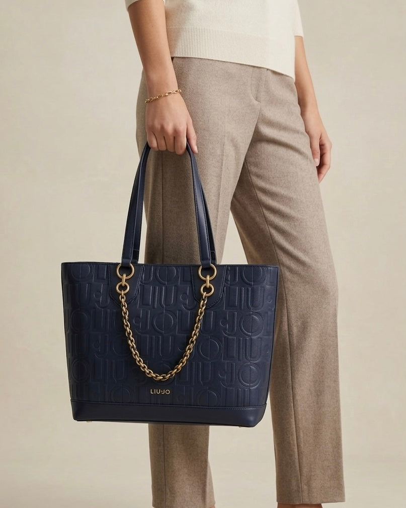 Borsa shopping Liu Jo blu navy con trama logo a rilievo, dettaglio catena dorata frontale e manici a spalla su sfondo bianco-indossata