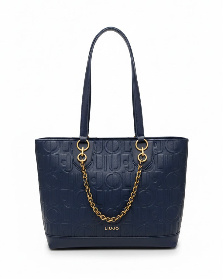 Borsa shopping Liu Jo blu navy con trama logo a rilievo, dettaglio catena dorata frontale e manici a spalla su sfondo bianco.
