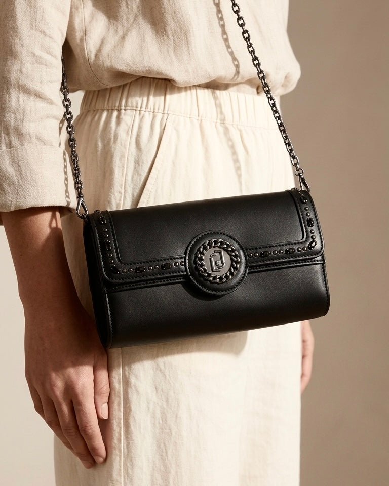 Borsa a tracolla Liu Jo nera con catena canna di fucile, logo circolare frontale e pattina decorata con pietre nere e borchie - Buttò Calzature - modella.