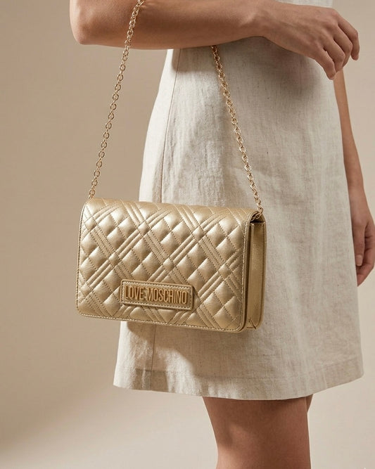 Borsa a tracolla Love Moschino trapuntata color oro con logo lettering e catena dorata-modella.