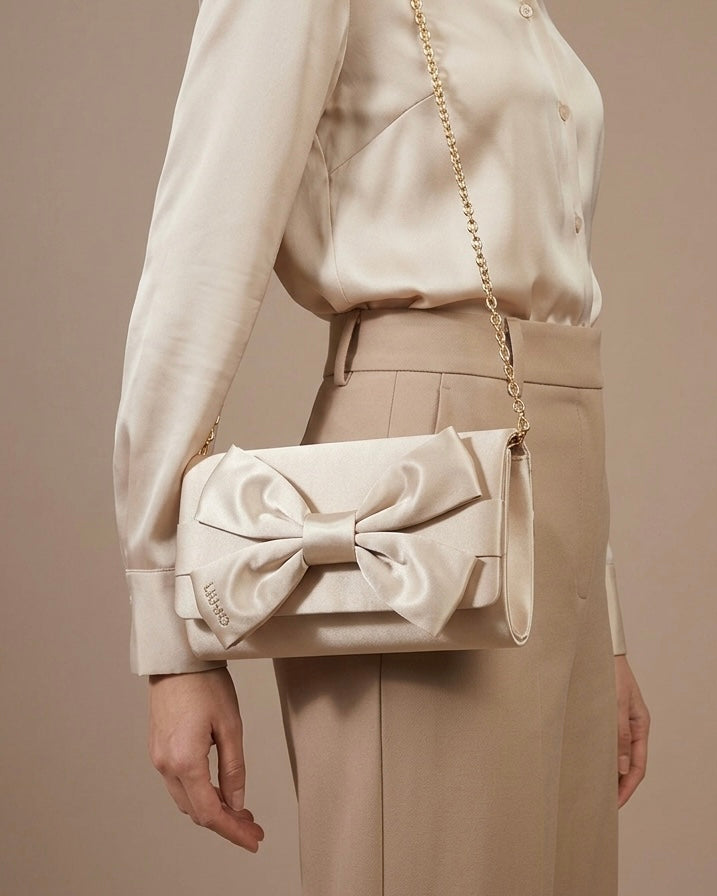 Pochette Liu Jo in satin beige con maxi fiocco frontale e tracolla a catena dorata-modella.