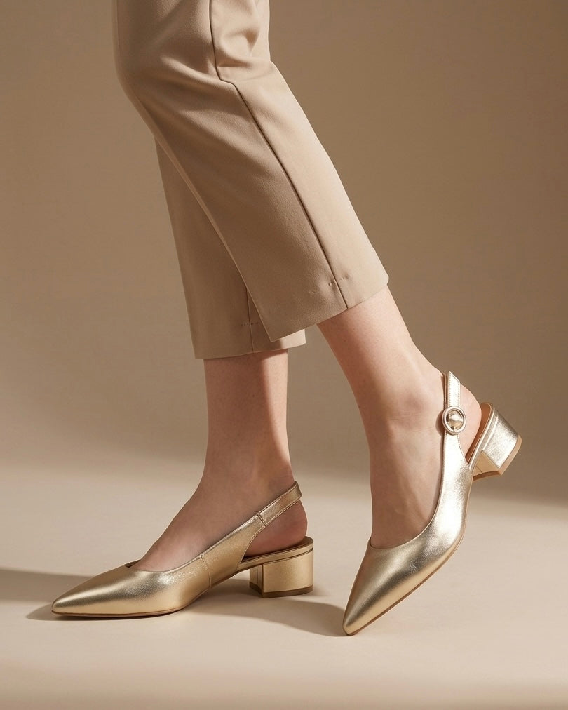 Scarpe eleganti modello slingback in finitura oro laminato, punta affusolata, tacco basso squadrato a blocco e cinturino regolabile con fibbia tonda-indossate.