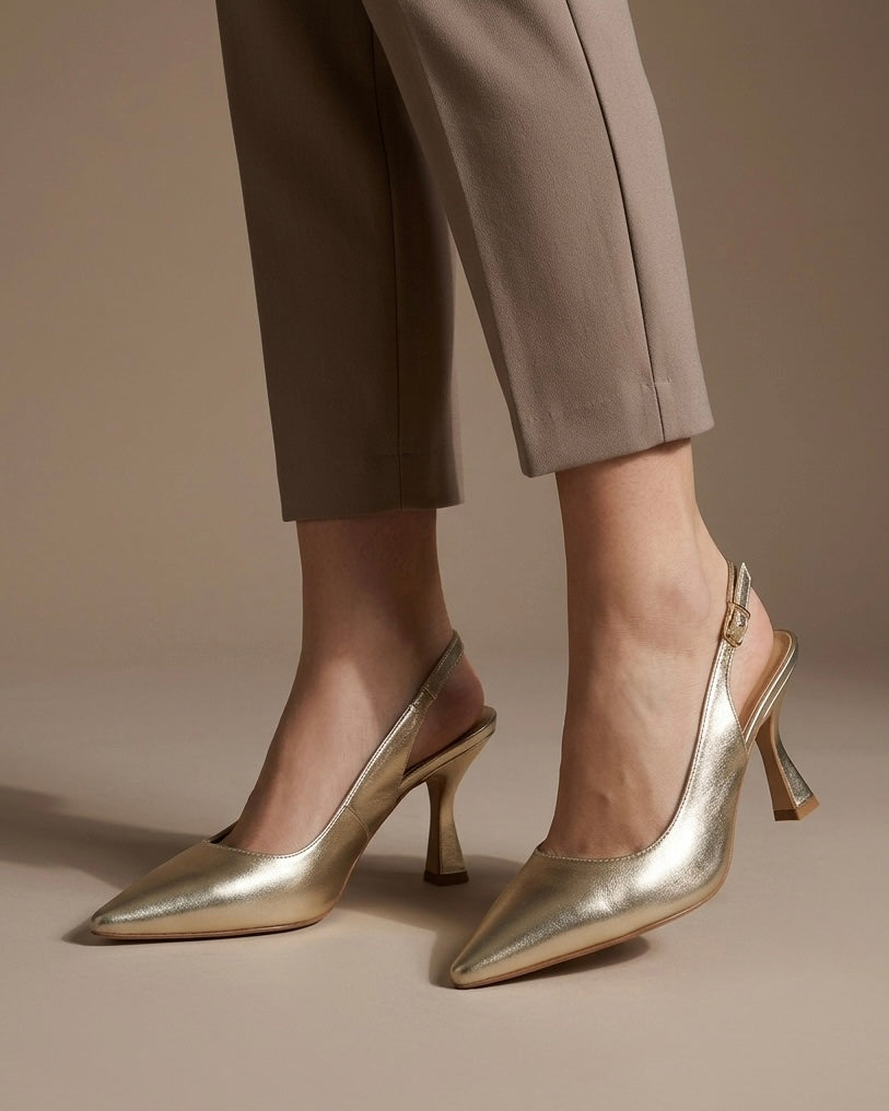Scarpe eleganti modello slingback in finitura oro laminato, punta affusolata, tacco medio a rocchetto e cinturino regolabile con fibbia dorata-indossate.