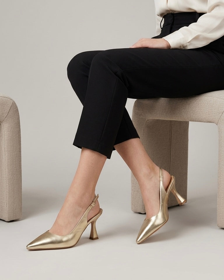 Scarpe eleganti modello slingback in finitura oro laminato, punta affusolata, tacco medio a rocchetto e cinturino regolabile con fibbia dorata-modella.