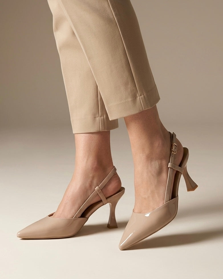 Scarpe eleganti modello slingback in vernice lucida color nude, punta sfilata affusolata, tacco alto sagomato a rocchetto e cinturino sottile regolabile con fibbia-indossate.