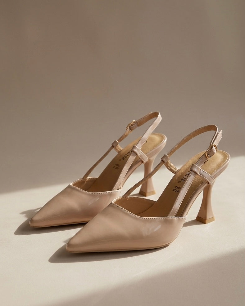 Scarpe eleganti modello slingback in vernice lucida color nude, punta sfilata affusolata, tacco alto sagomato a rocchetto e cinturino sottile regolabile con fibbia.