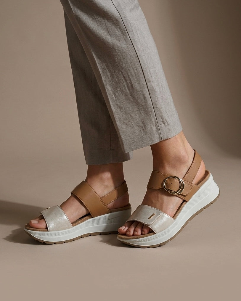 Sandali da donna Igi&Co in vera pelle panna e cuoio, con maxi fibbia tonda dorata, cinturino regolabile e zeppa leggera ammortizzata-indossati.