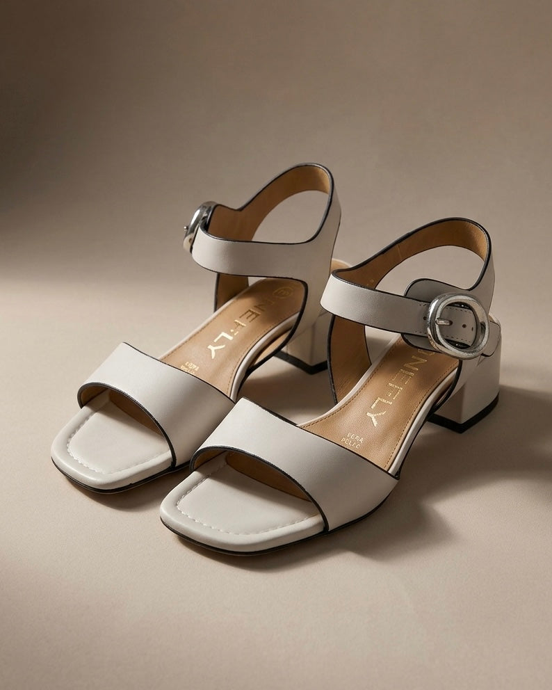Sandali donna Stonefly in vera pelle color bianco panna con tacco medio largo, profili neri e cinturino alla caviglia con fibbia argento.