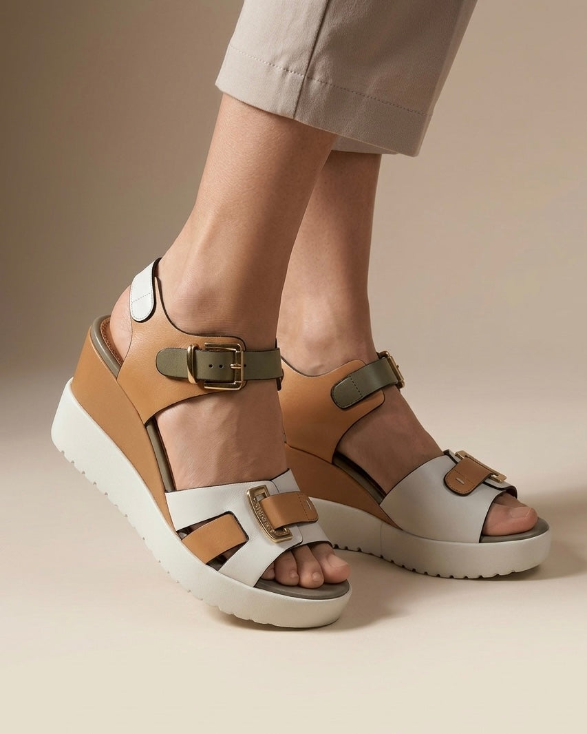 Sandali donna Stonefly con zeppa platform bianca, fasce in pelle bianca, cuoio e fango con grandi fibbie dorate logate-indossate.