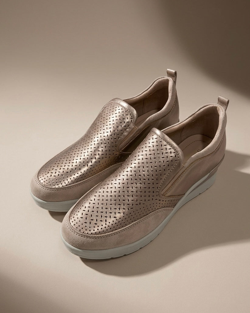 Scarpe slip-on donna Stonefly color bronzo metallizzato con tomaia traforata a laser, inserti elastici laterali e suola platform chiara.