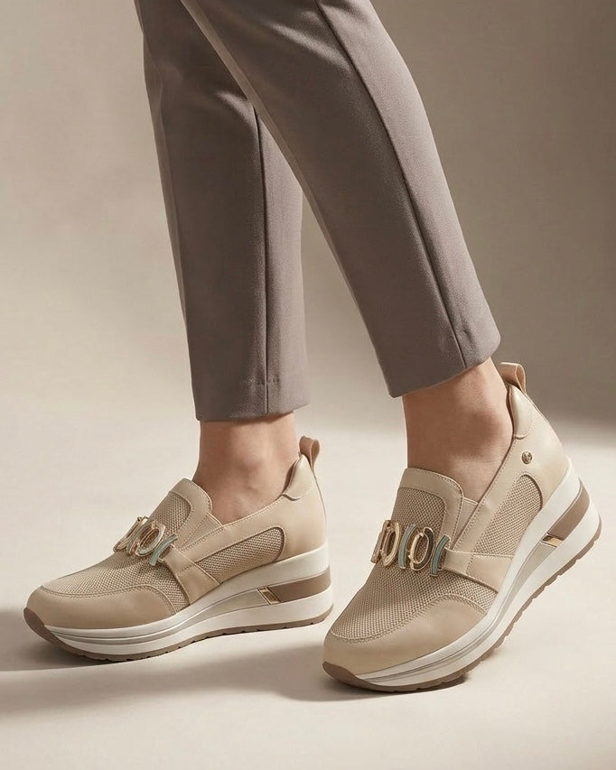 Sneakers slip-on marca Donna Serena color beige sabbia, con maxi morsetto dorato sulla parte frontale, inserti in mesh e suola platform alta-indossate.