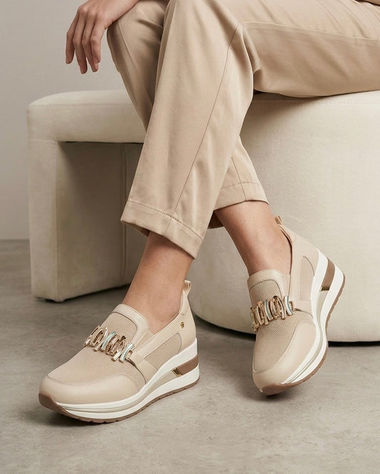 Sneakers slip-on marca Donna Serena color beige sabbia, con maxi morsetto dorato sulla parte frontale, inserti in mesh e suola platform alta.-modella.