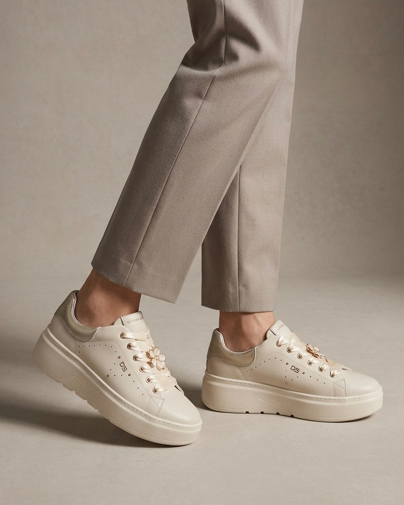 Sneakers platform da donna Donna Serena color panna in pelle, con lacci larghi in raso lucido, applicazione a forma di fiore gioiello e tallone argentato-indossate.