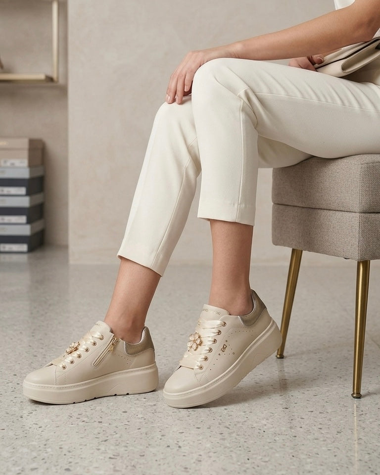 Sneakers platform da donna Donna Serena color panna in pelle, con lacci larghi in raso lucido, applicazione a forma di fiore gioiello e tallone argentato-modella.