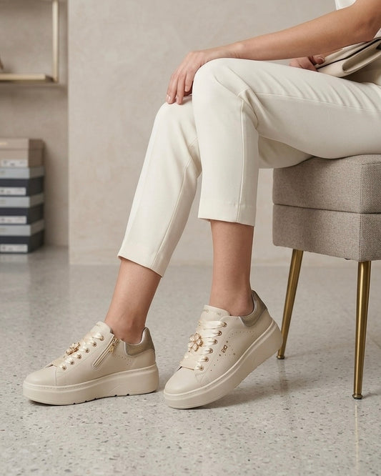 Sneakers platform da donna Donna Serena color panna in pelle, con lacci larghi in raso lucido, applicazione a forma di fiore gioiello e tallone argentato-modella.