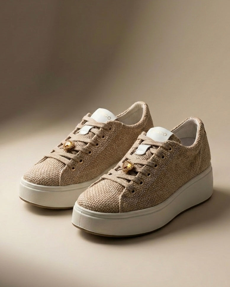Sneakers da donna marca Igi&Co color beige panna con tomaia a texture intrecciata effetto rafia, cuori dorati metallizzati applicati sui lacci e suola platform bianca.