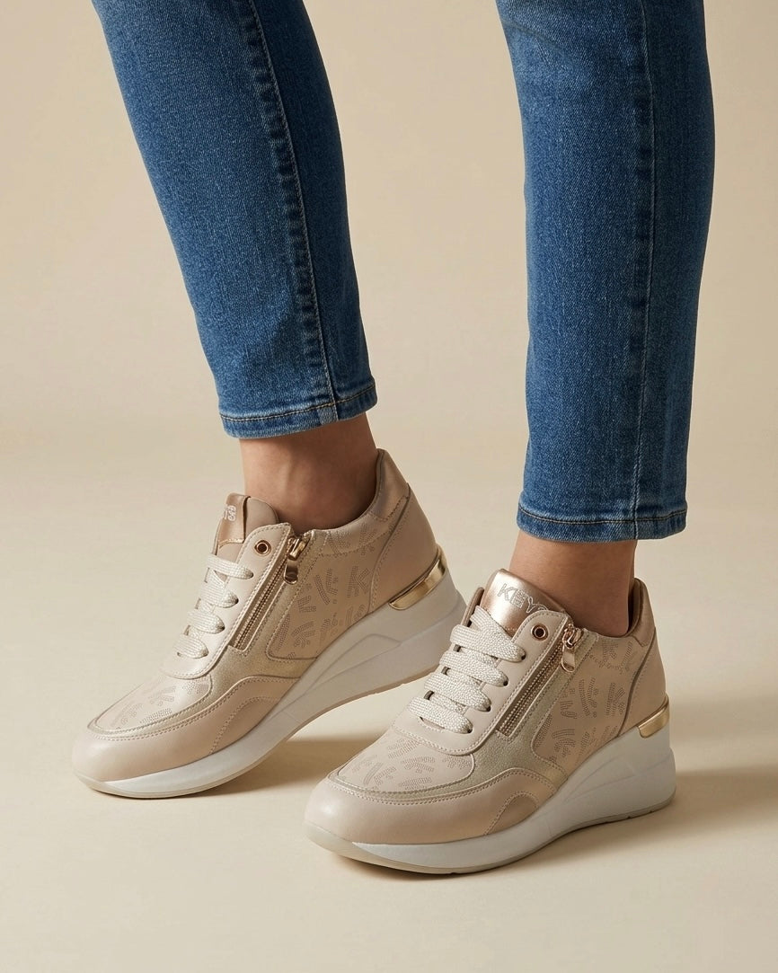 Sneakers Keys da donna color beige champagne con stampa monogram all-over, dettagli laminati oro, doppia zip laterale e suola chunky bianca - indossata.