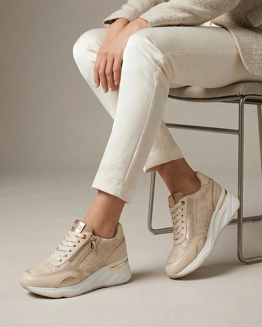 Sneakers Keys da donna color beige champagne con stampa monogram all-over, dettagli laminati oro, doppia zip laterale e suola chunky bianca -indossate modella.