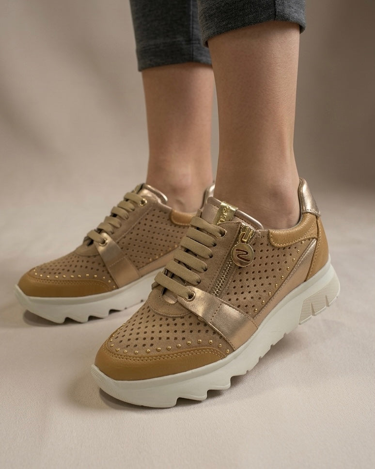 Sneakers Stonefly da donna color sabbia con pelle traforata, dettagli laminati oro, suola bianca sagomata e pratica zip laterale-indossate.