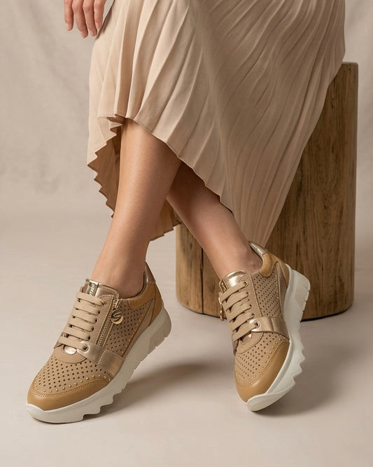 Sneakers Stonefly da donna color sabbia con pelle traforata, dettagli laminati oro, suola bianca sagomata e pratica zip laterale-modella.
