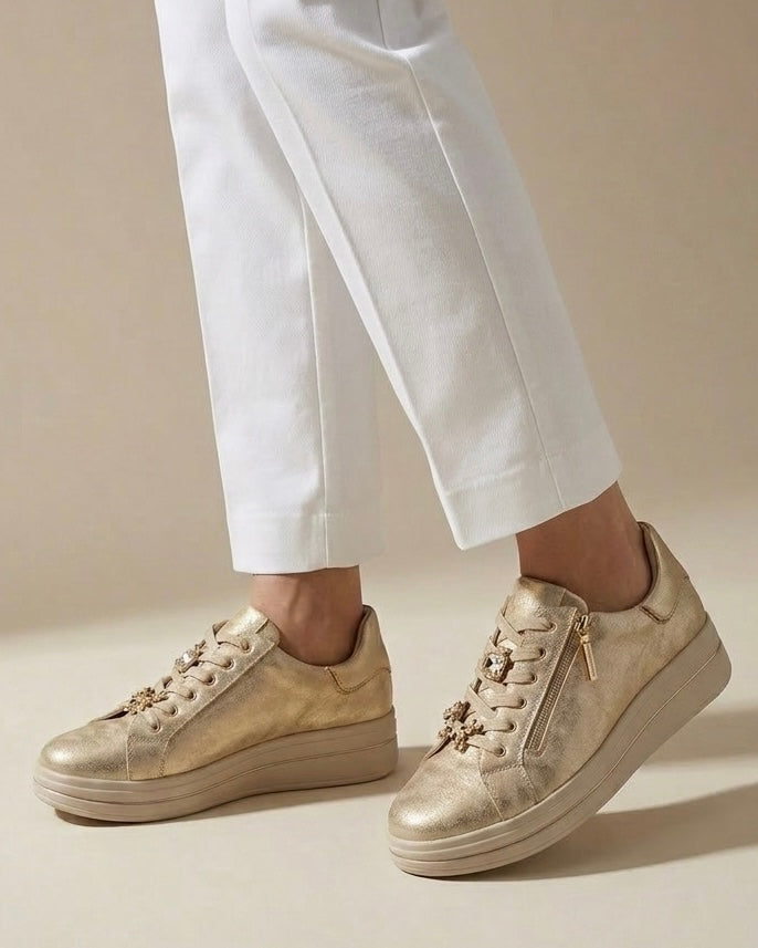 Sneakers da donna marca Valleverde color oro metallizzato, lacci in tinta con applicazioni gioiello a forma di leopardo e strass, pratica zip laterale e suola platform beige-indossate.