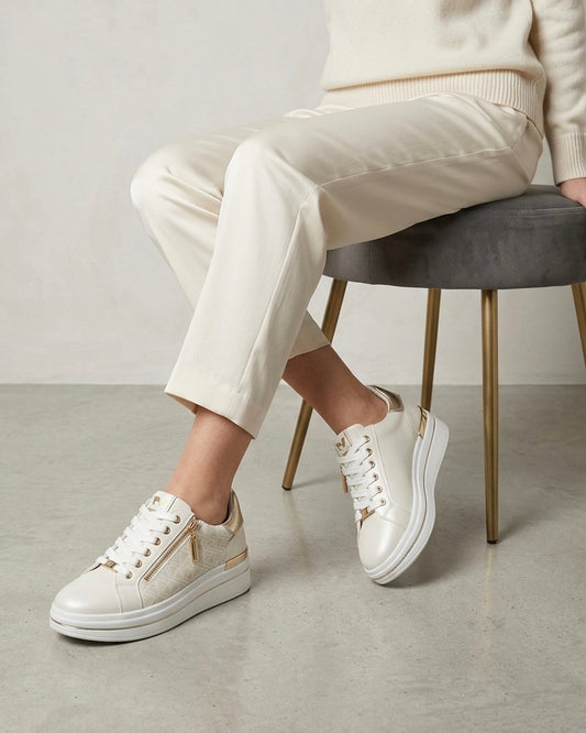 Sneakers da donna brand Valleverde color panna e bianco, con tomaia traforata al laser, inserti oro platino sul tallone e pratica zip laterale-modella.
