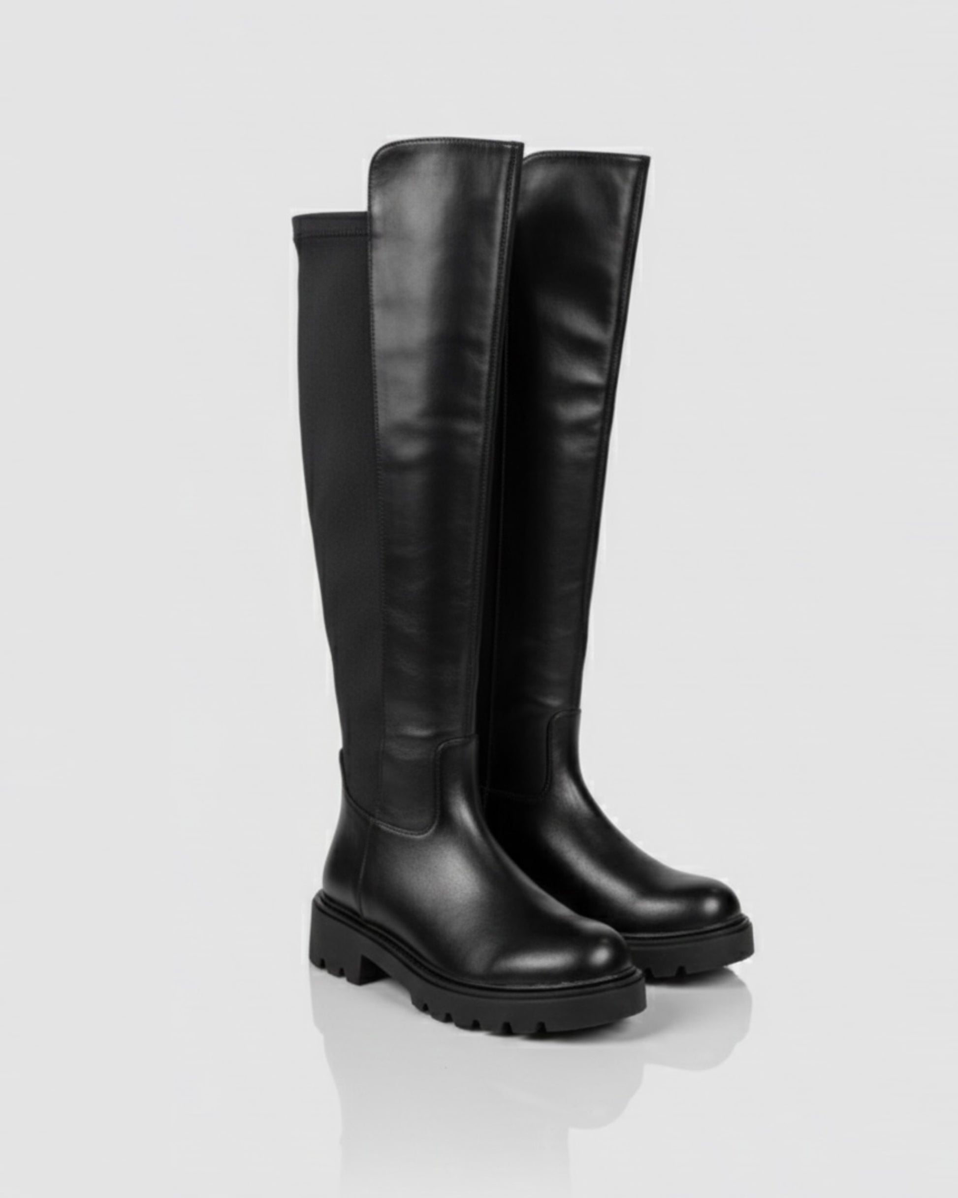 Stivali alti sopra il ginocchio in pelle nera con inserto elastico posteriore e suola chunky a carrarmato.