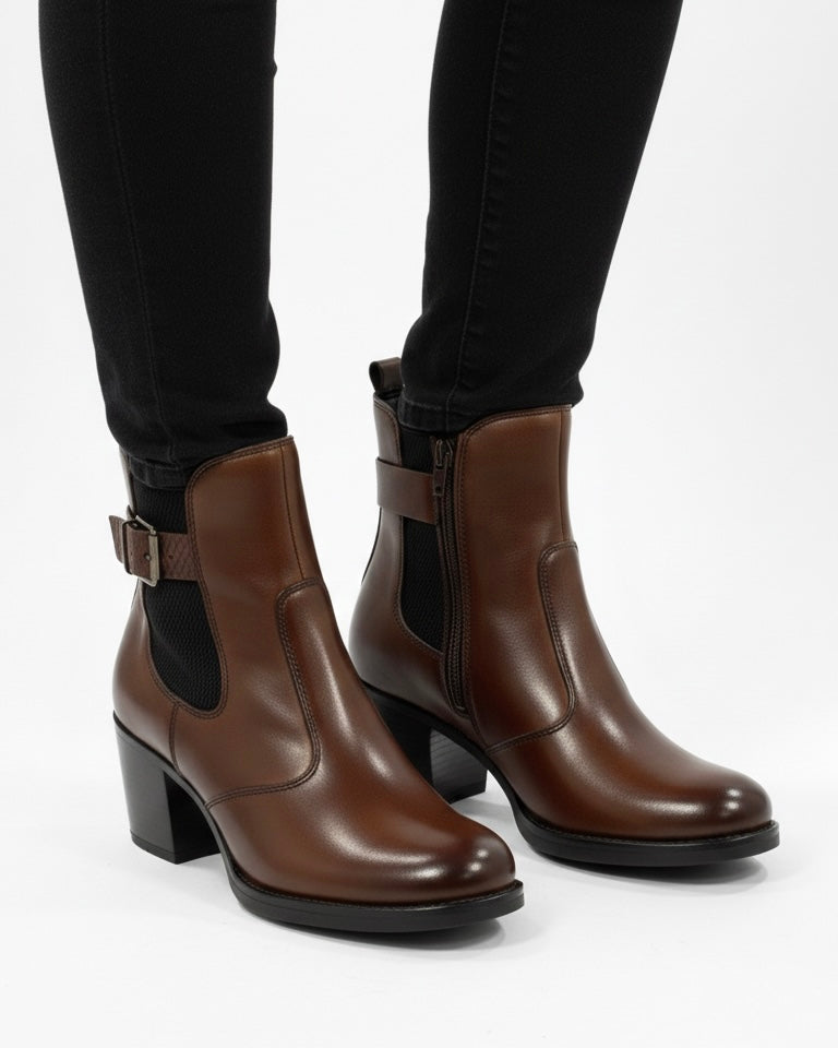 Stivaletti chelsea da donna in pelle marrone scuro con tacco largo e fibbia laterale decorativa  indossati.